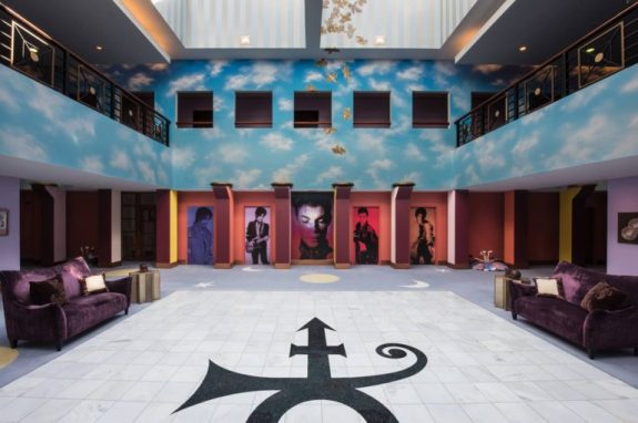 Via this site the room was much like this, but the doors with Prince paintings have been replaced with memorabilia displays and a pedistal with a Paisley Park model and his remains now sits in the center of the photo.